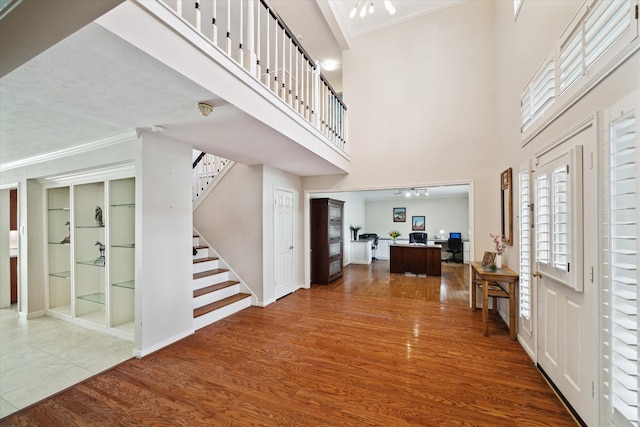 foyer featuring hardwood / wood-style flooring, a towering ceiling, and crown molding