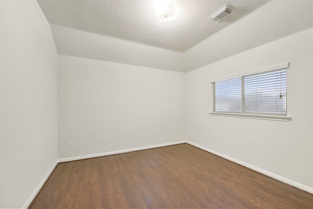 unfurnished room with dark wood-style floors, visible vents, a textured ceiling, and baseboards