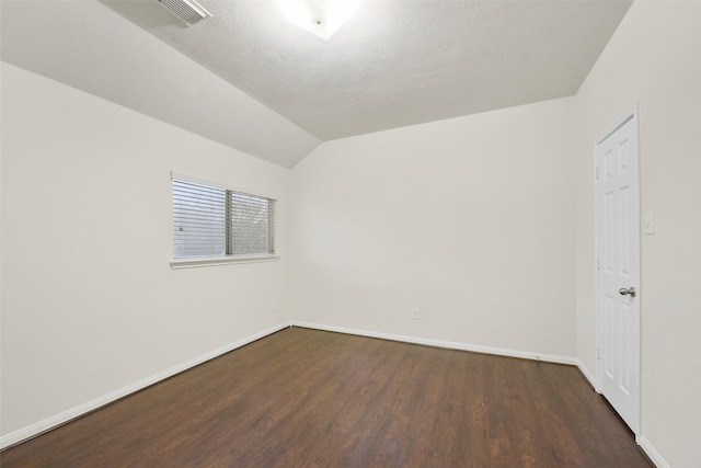 empty room featuring lofted ceiling, baseboards, visible vents, and dark wood-style flooring