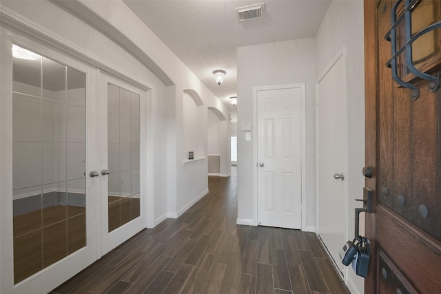 interior space with arched walkways, baseboards, visible vents, and wood tiled floor