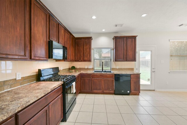 kitchen featuring sink, tasteful backsplash, light tile patterned floors, light stone countertops, and black appliances