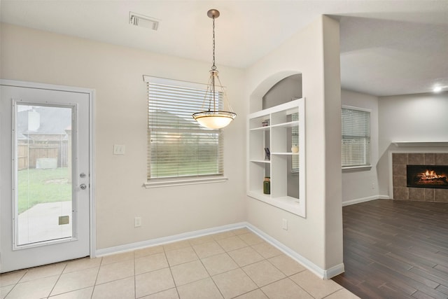 unfurnished dining area featuring built in shelves, visible vents, a fireplace, and baseboards