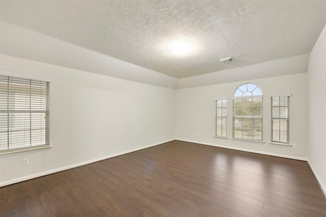 empty room with dark hardwood / wood-style floors and a textured ceiling