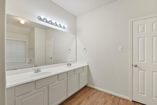 bathroom with double vanity, a sink, baseboards, and wood finished floors