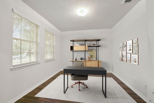 home office with a textured ceiling, baseboards, visible vents, and wood tiled floor