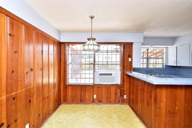 kitchen with sink, wood walls, cooling unit, tile counters, and pendant lighting