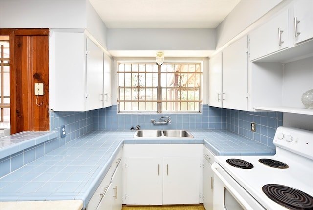 kitchen featuring sink, white range with electric cooktop, tasteful backsplash, white cabinets, and tile countertops