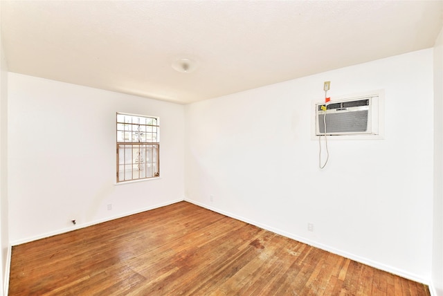 unfurnished room with hardwood / wood-style flooring and an AC wall unit