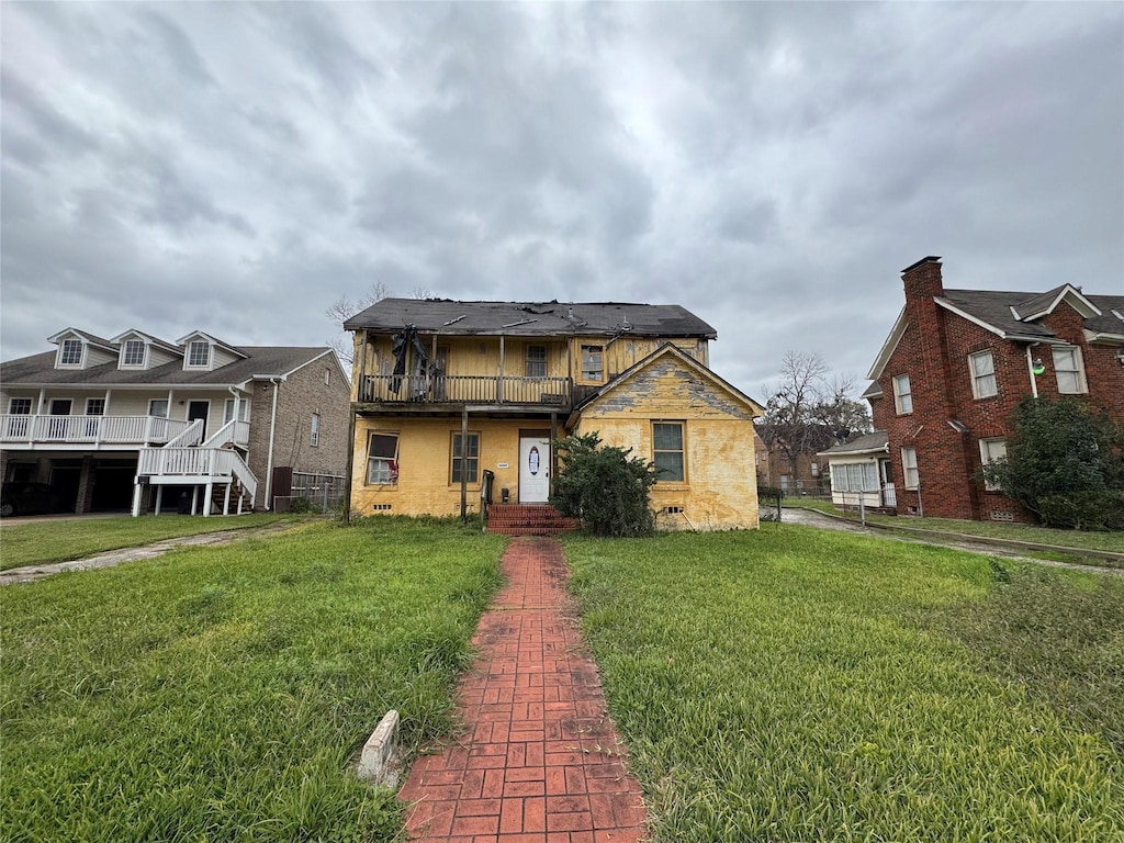 view of front of property featuring a balcony and a front yard