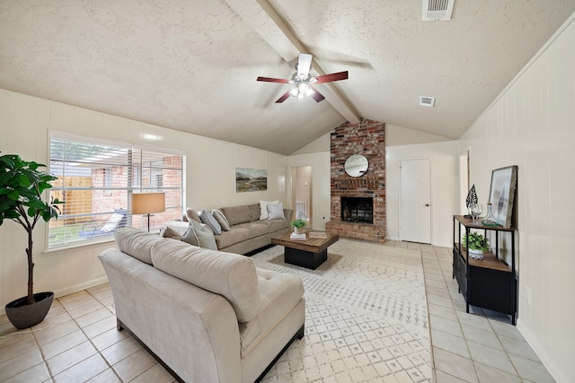 tiled living room with ceiling fan, a fireplace, lofted ceiling with beams, and a textured ceiling