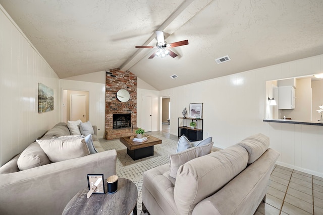 living room with a fireplace, lofted ceiling with beams, light tile patterned floors, ceiling fan, and a textured ceiling