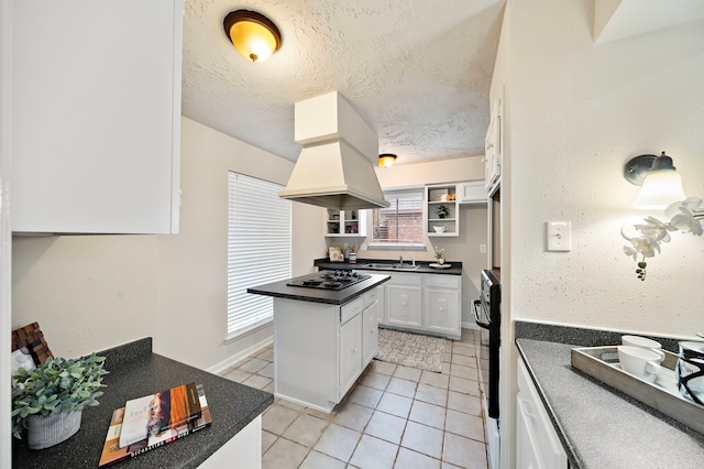 kitchen with island range hood, white cabinets, light tile patterned floors, black appliances, and a textured ceiling