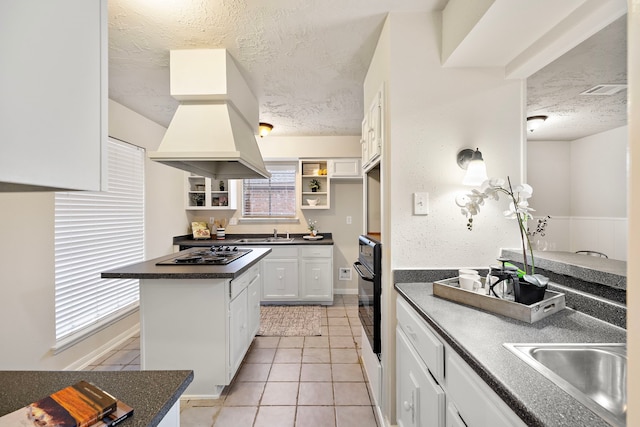 kitchen with sink, black appliances, a textured ceiling, white cabinets, and light tile patterned flooring