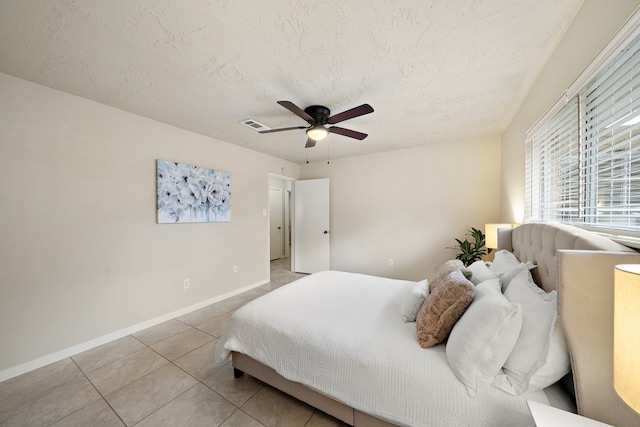 bedroom featuring ceiling fan, light tile patterned floors, and a textured ceiling