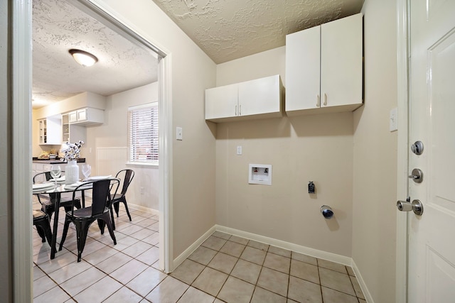 laundry room featuring light tile patterned flooring, cabinets, a textured ceiling, electric dryer hookup, and washer hookup