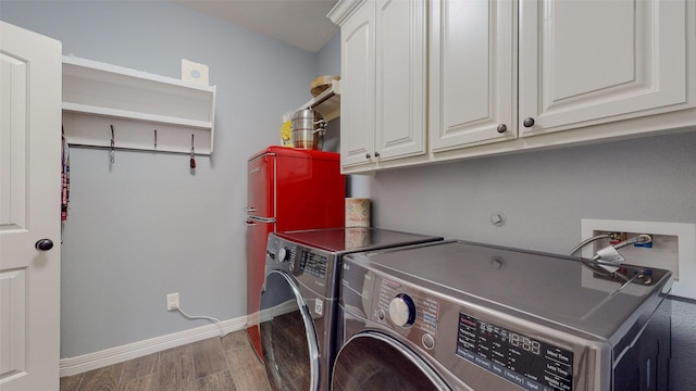 laundry area with cabinets, wood-type flooring, and washer and dryer