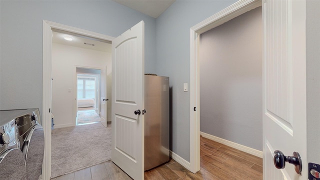 clothes washing area featuring washing machine and clothes dryer and light hardwood / wood-style floors