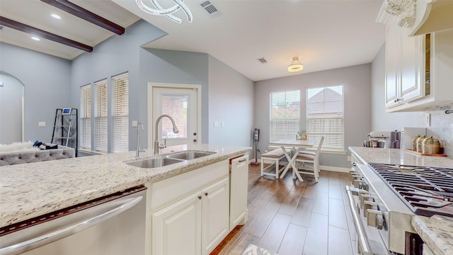 kitchen with sink, appliances with stainless steel finishes, light stone countertops, light hardwood / wood-style floors, and white cabinets