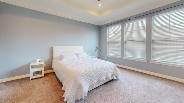 bedroom featuring ornamental molding, a tray ceiling, and light carpet