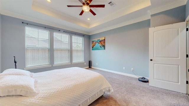 carpeted bedroom with crown molding and a tray ceiling