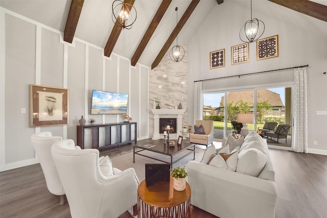 living room featuring hardwood / wood-style floors, a high end fireplace, an inviting chandelier, and high vaulted ceiling