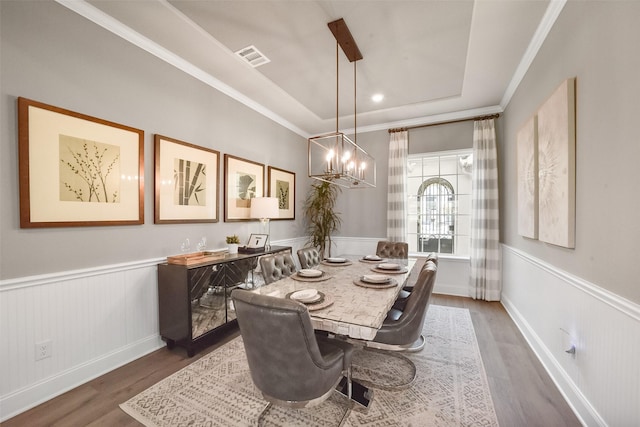 dining space featuring a tray ceiling, dark wood-type flooring, ornamental molding, and a chandelier