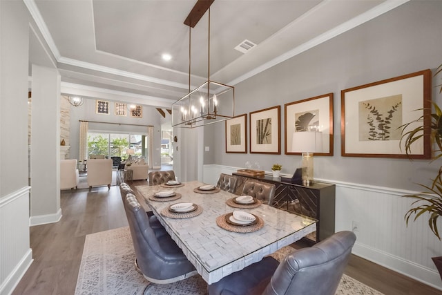 dining room with hardwood / wood-style floors, crown molding, a notable chandelier, and a raised ceiling