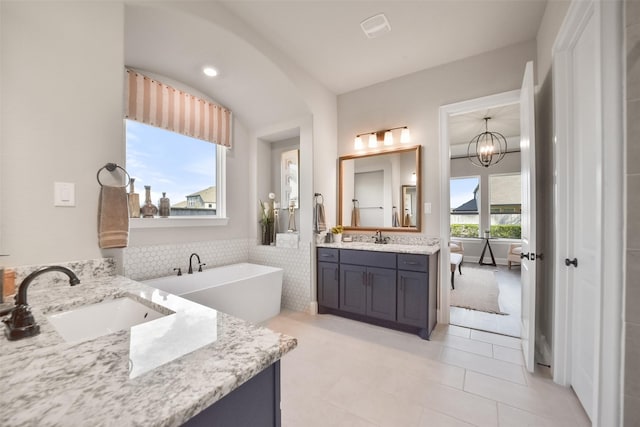 bathroom featuring vanity, a bath, tile patterned floors, and a chandelier