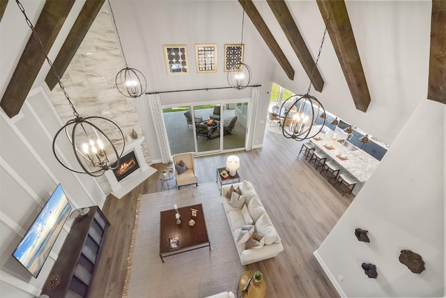 living room with a notable chandelier, beam ceiling, high vaulted ceiling, and a large fireplace