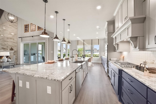 kitchen with decorative light fixtures, sink, decorative backsplash, a large island, and stainless steel appliances