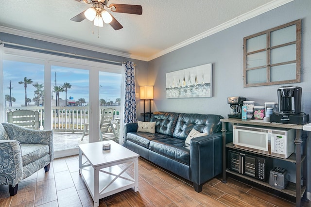 living room featuring crown molding, ceiling fan, wood-type flooring, and a textured ceiling