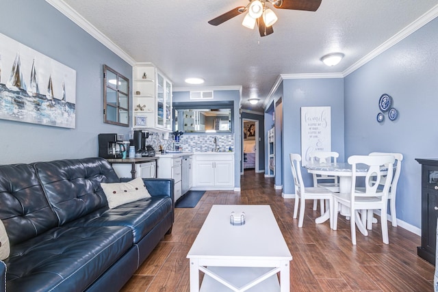 living room with ceiling fan, ornamental molding, wet bar, and a textured ceiling