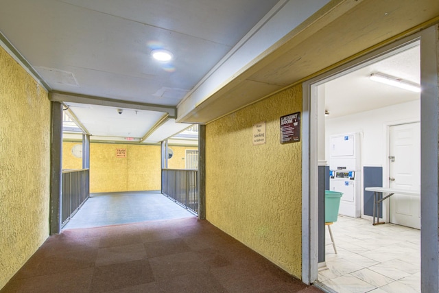 corridor featuring stacked washer / drying machine