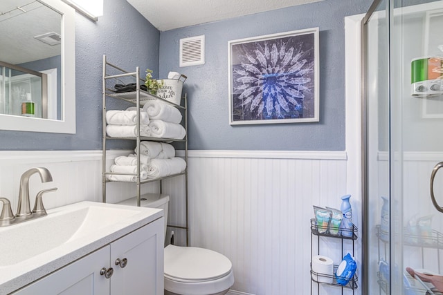 bathroom featuring walk in shower, vanity, and toilet