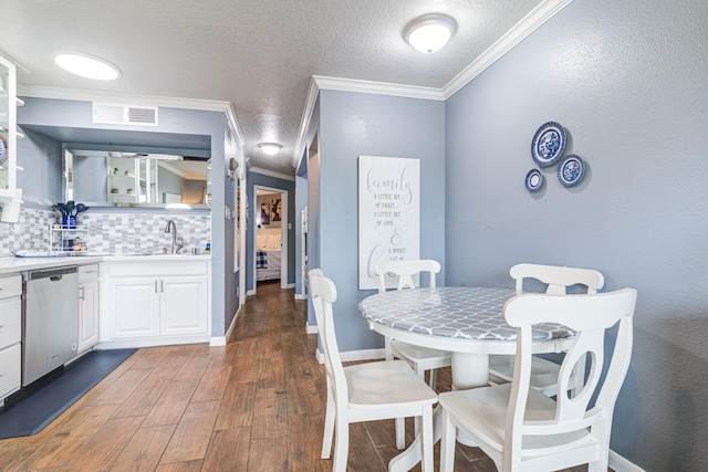 dining space with dark hardwood / wood-style flooring, indoor wet bar, ornamental molding, and a textured ceiling