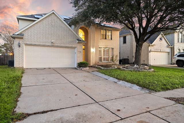 view of front property featuring cooling unit, a garage, and a yard