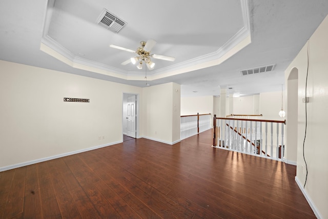 empty room with ceiling fan, ornamental molding, dark hardwood / wood-style floors, and a raised ceiling