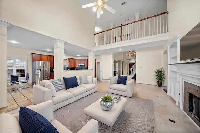 living room with decorative columns, light tile patterned flooring, a high ceiling, and ceiling fan