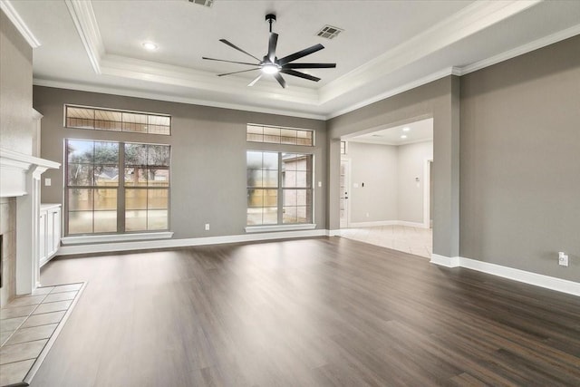 unfurnished living room with a raised ceiling, a tile fireplace, and plenty of natural light