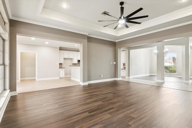 unfurnished living room featuring dark hardwood / wood-style floors, ceiling fan with notable chandelier, and a raised ceiling