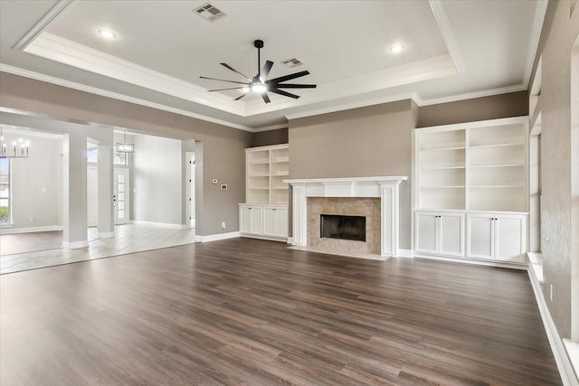 unfurnished living room featuring dark hardwood / wood-style flooring, ceiling fan with notable chandelier, a fireplace, and a raised ceiling