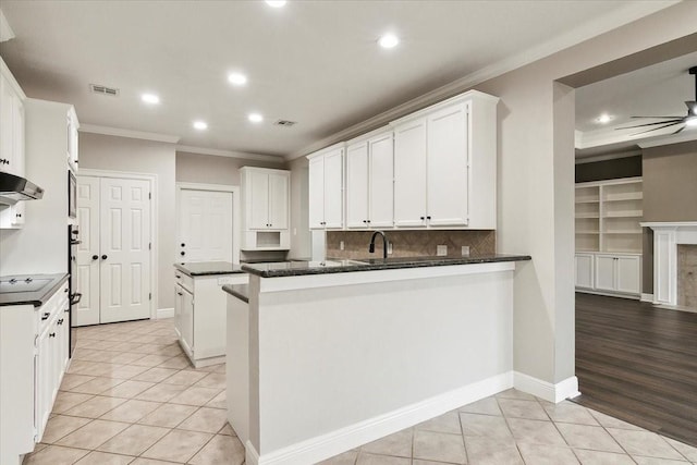 kitchen featuring white cabinetry, crown molding, kitchen peninsula, and light tile patterned floors