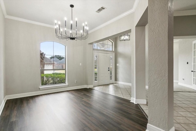 foyer entrance with hardwood / wood-style flooring, ornamental molding, and an inviting chandelier