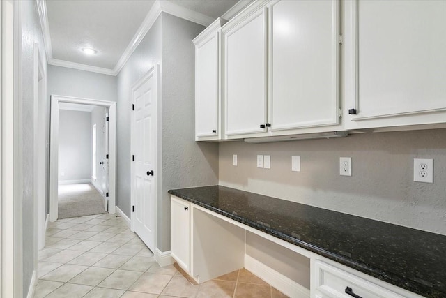 interior space featuring white cabinetry, light tile patterned floors, built in desk, and dark stone countertops