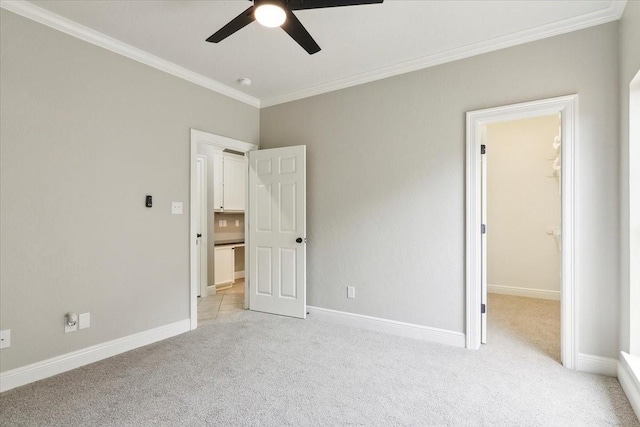 unfurnished bedroom with crown molding, light colored carpet, ceiling fan, and a spacious closet