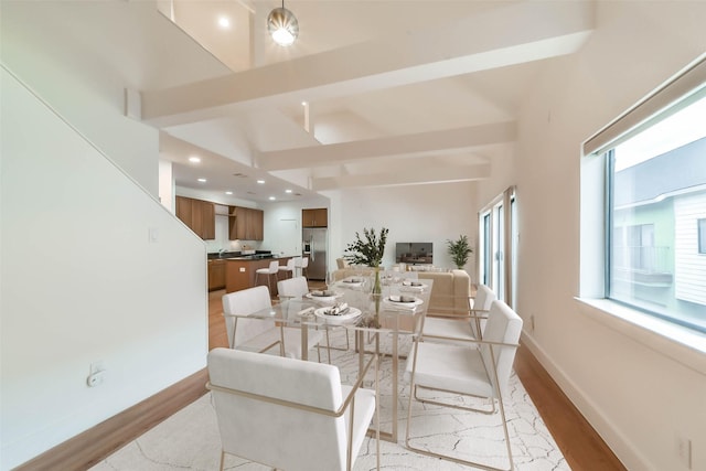 dining space with beam ceiling and light hardwood / wood-style floors