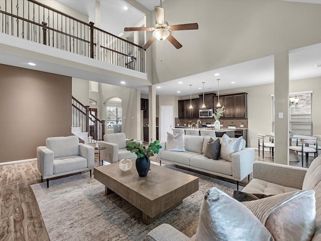 living room with sink, dark wood-type flooring, and ceiling fan with notable chandelier