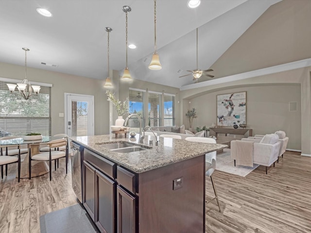 kitchen with light stone counters, light hardwood / wood-style floors, sink, and dark brown cabinets