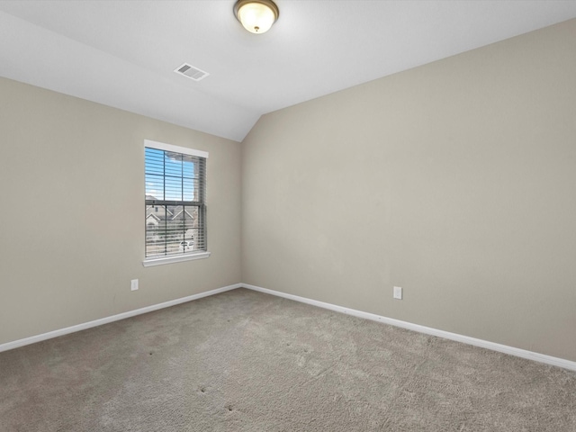 carpeted empty room featuring vaulted ceiling