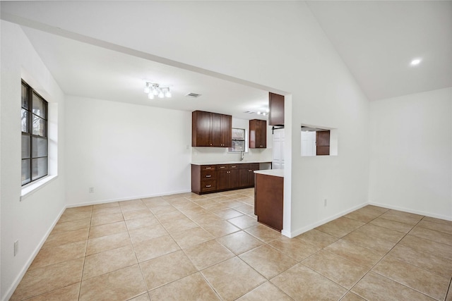 kitchen featuring light tile patterned flooring, dark brown cabinets, sink, and high vaulted ceiling